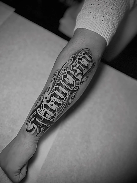 Lettering estilo chicano con volumen y sombra a lo largo del antebrazo