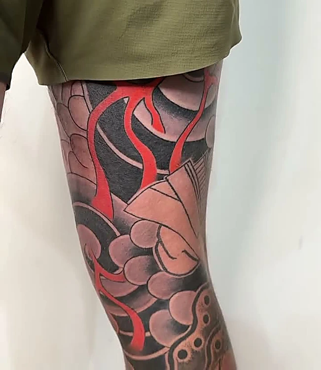 Pierna con fondo japonés en negro y gris y llamas rojas, trabajo en proceso