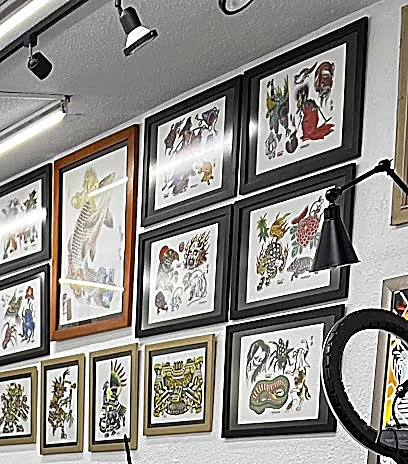 Muro blanco del estudio cubierto de diseños de flash enmarcados, con lámparas de riel