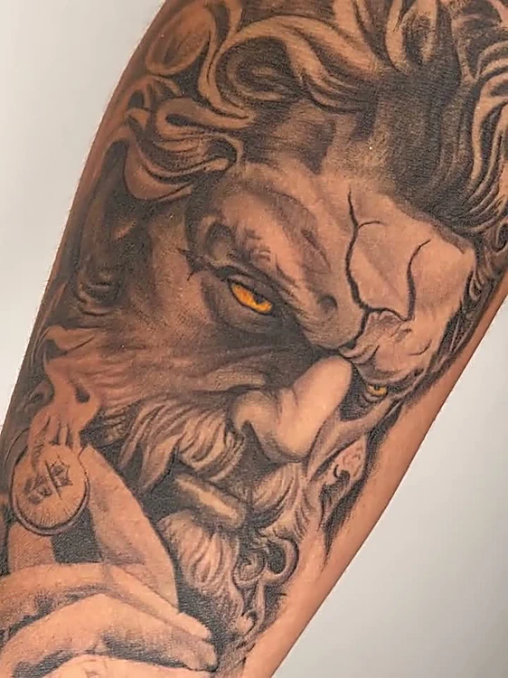 Poseidón en negro y gris con ojos ámbar, realismo en el antebrazo