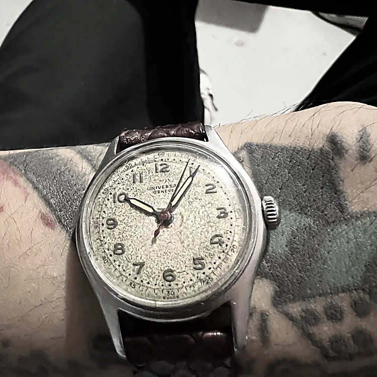Reloj de pulsera antiguo junto a un tatuaje de reloj en negro y gris