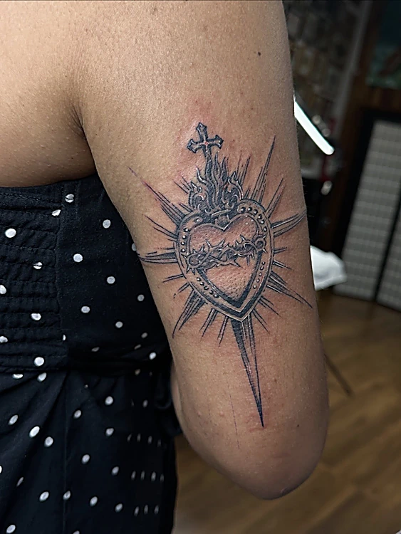Sagrado corazón con cruz y rayos en línea negra en la parte trasera del brazo