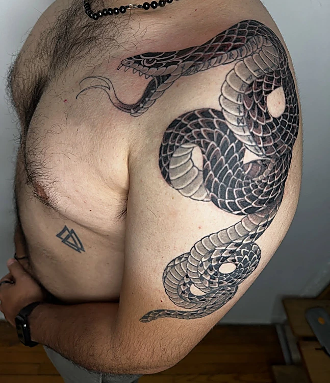 Serpiente en blackwork que rodea el hombro y baja por el pecho
